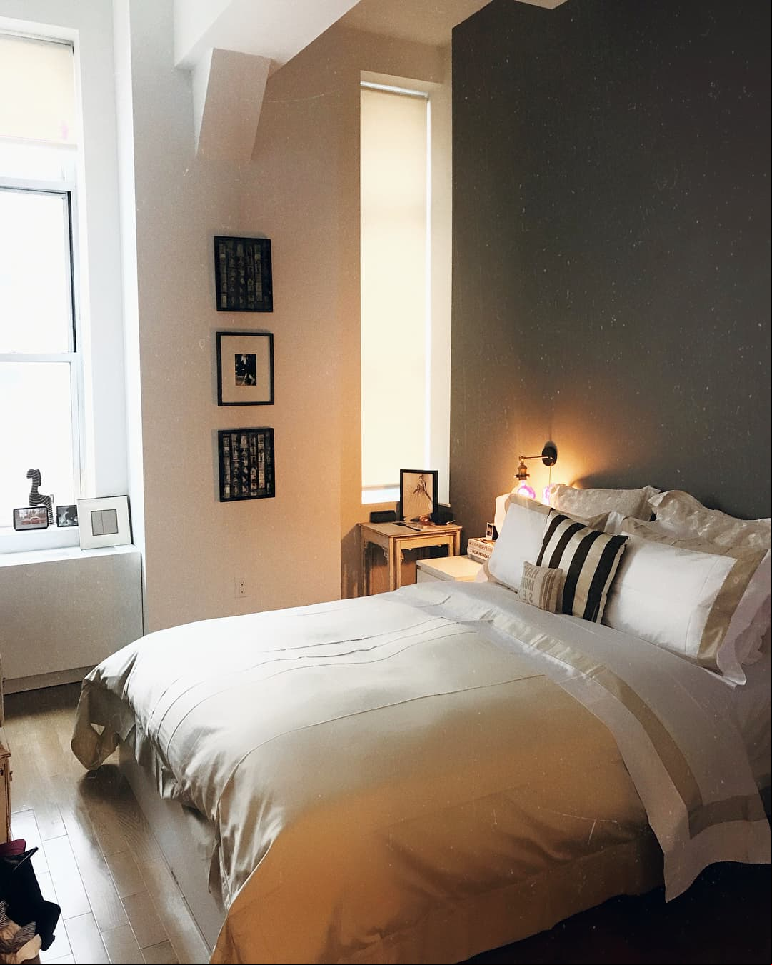 El cuarto tiene las paredes pintadas de gris y blanco, hecho que combina a la perfección con los cuadros monocromáticos, los burós, el edredón y almohadas que son de las mismas tonalidades.