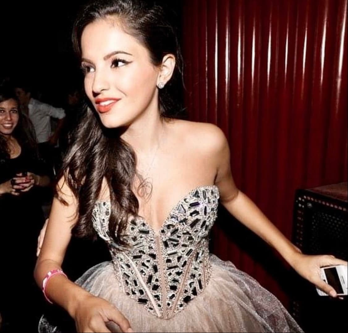 El vestido de la entonces quinceañera fue en diseño bustier, el cual se dividía en dos partes; la superior decorada con piedras brillantes y la parte inferior con una falda en tela de tul.