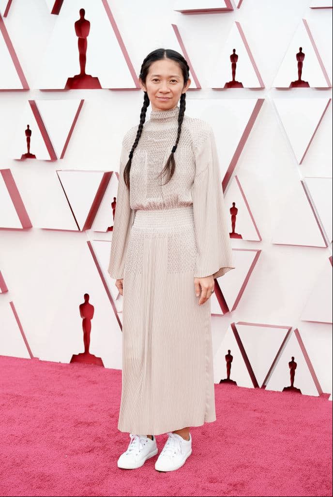 Chloé Zhao optó por un vestido indie de color terracota, el cual complementó con unos tenis de color blanco.