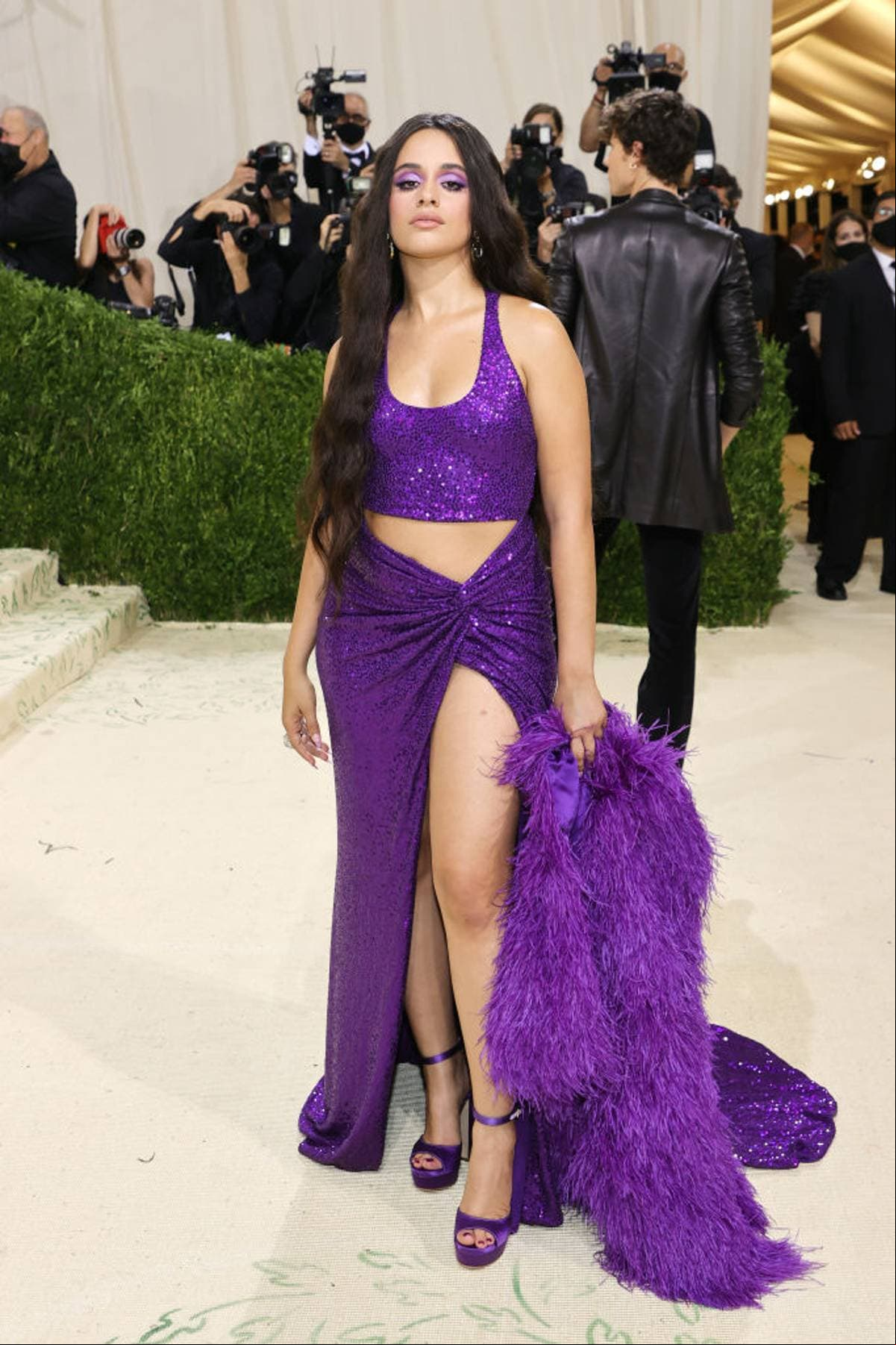 Camila Cabello sorprendió con un vestido morado de dos piezas de la firma Michael Kors. Además lo combinó perfecto con un abrigo de peluche y zapatillas moradas.