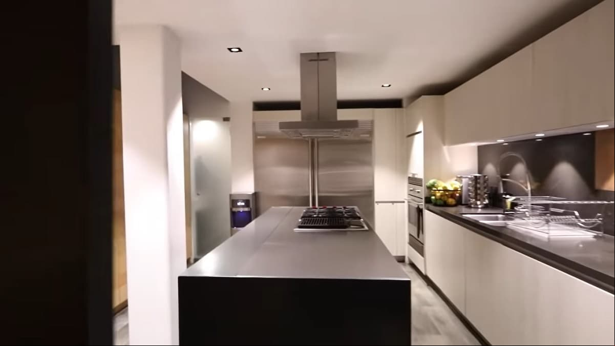La cocina tiene una pequeña isla, que sirve como desayunador y para preparar los alimentos; además de que está decorada en tonos blancos, que hacen juego con los electrodomésticos de acero inoxidable.