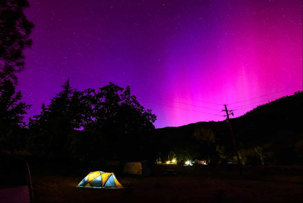 TOPSHOT - Northern lights or aurora borealis illuminate the night sky over a camper's tent north of San Francisco in Middletown, California on May 11, 2024. The most powerful solar storm in more than two decades struck Earth, triggering spectacular celestial light shows from Tasmania to Britain -- and threatening possible disruptions to satellites and power grids as it persists into the weekend. (Photo by JOSH EDELSON / AFP) (Photo by JOSH EDELSON/AFP via Getty Images)