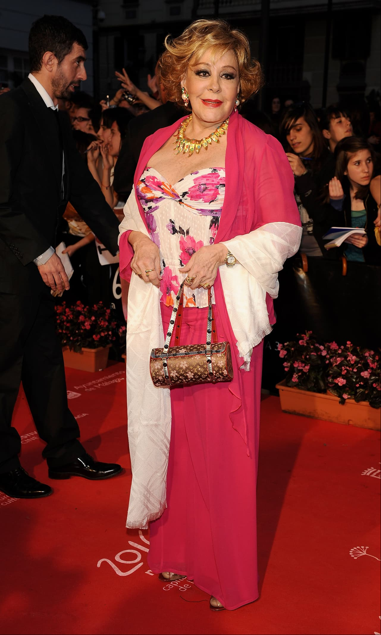 Uno de nuestros indiscutibles favoritos es este outfit que la actriz lució en abril 2009 en la ceremonia de inauguración del 'Málaga Film Festival'. Un atuendo de tres piezas compuesto por una falda larga en rosa mexicana, una blusa floreada con detalles en el mismo tono y una pashmina también rosa mexicano que resaltan a la perfección su tez y tono de pelo. Los detalles en dorado, le dan un toque glamouroso e ideal para el evento.