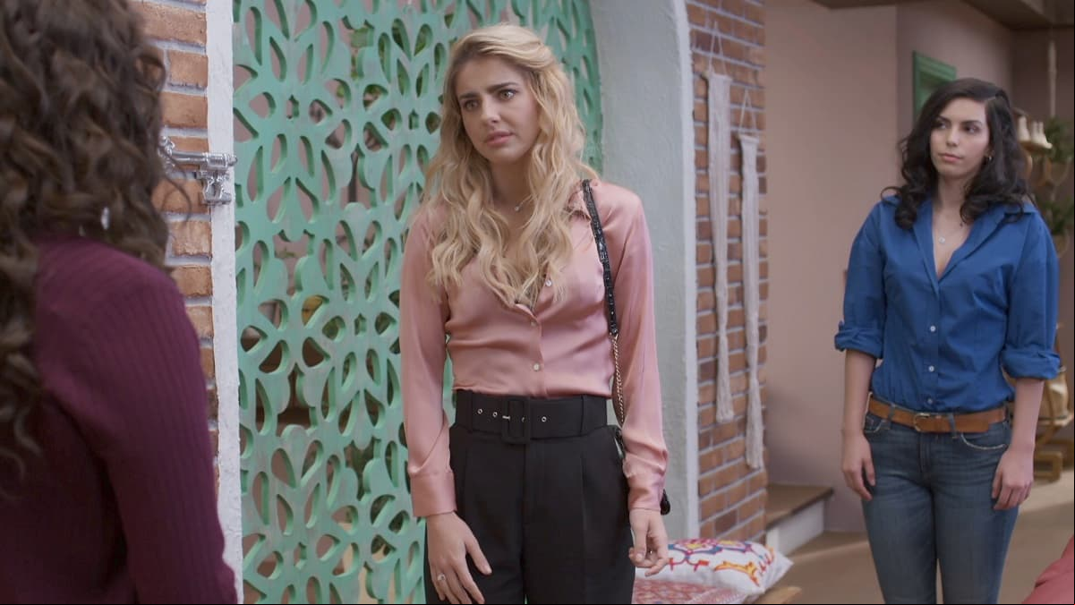 En esta imagen, Michelle Renaud luce una blusa de manga larga en rosa en una excelente combinación con pantalones negros de tiro alto.