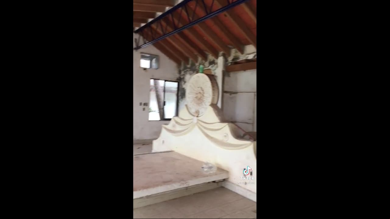 Lo que parece ser la habitación principal cuenta con techo de madera y una recámara realizada a la medida con una amplia cabecera con un tipo medallón en la parte superior.