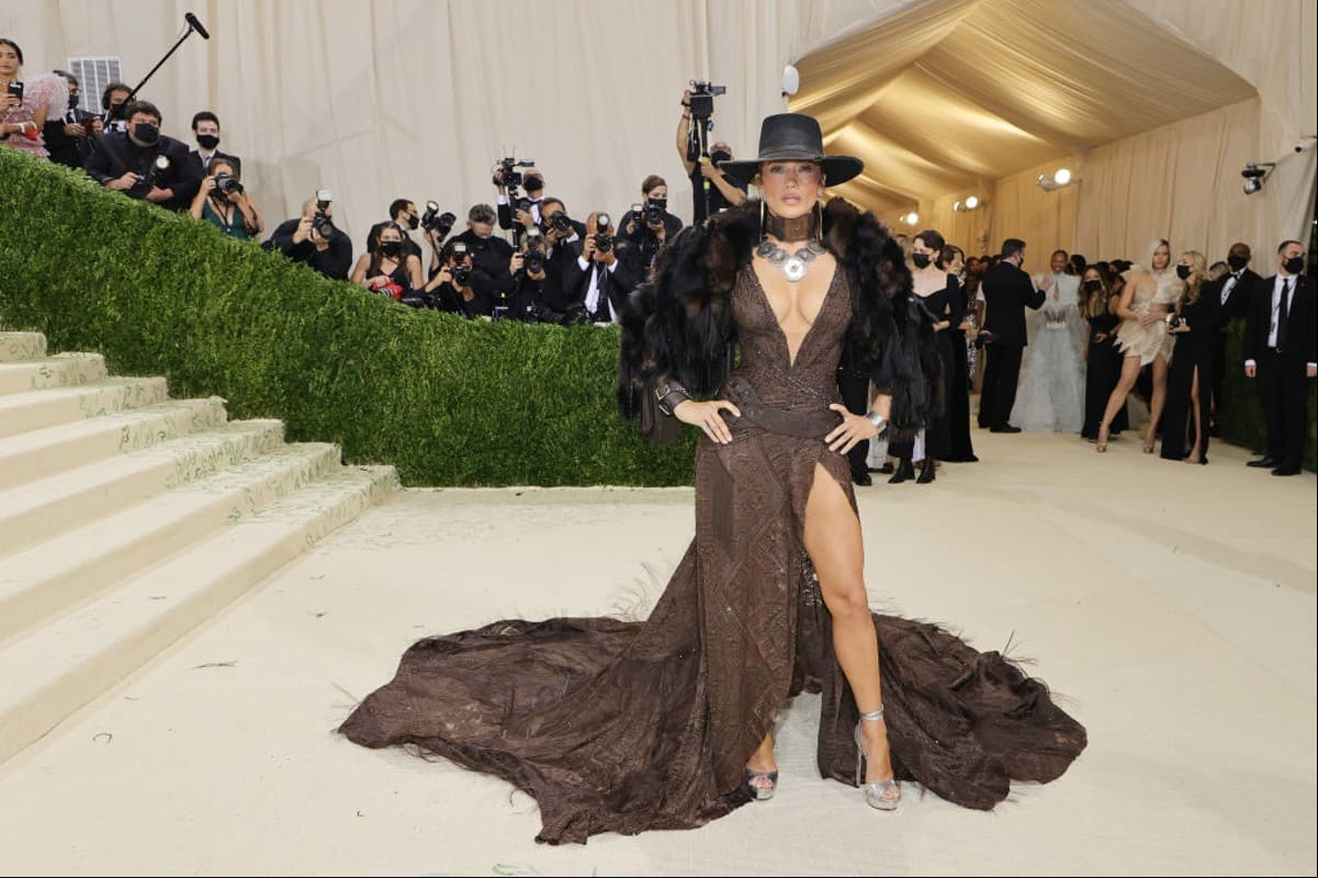 Como toda una estrella de Hollywood, Jennifer Lopez robó miradas con su espectacular vestido Ralph Lauren en tonos cafés y un escote profundo, el cual complementó con un abrigo de peluche, aretes y gargantilla de plata, además de un cinturón de piel. El rio que más llamó la atención fue el sombrero negro que portó.