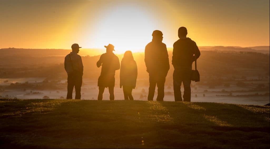 GLASTONBURY, ENGLAND - SEPTEMBER 22: People watch as the autumn sun rises over the Somerset Levels viewed from Glastonbury Tor near Glastonbury on September 22, 2017 in Somerset, England. Today marks the start of the astronomical autumn, which is defined by the Earth's axis and orbit around the sun. The transition from summer to autumn is defined by the autumn equinox, when day and night are of roughly equal length, but also signals that the nights will become increasingly longer than the days until the spring equinox, when the pattern is reversed. (Photo by Matt Cardy/Getty Images)