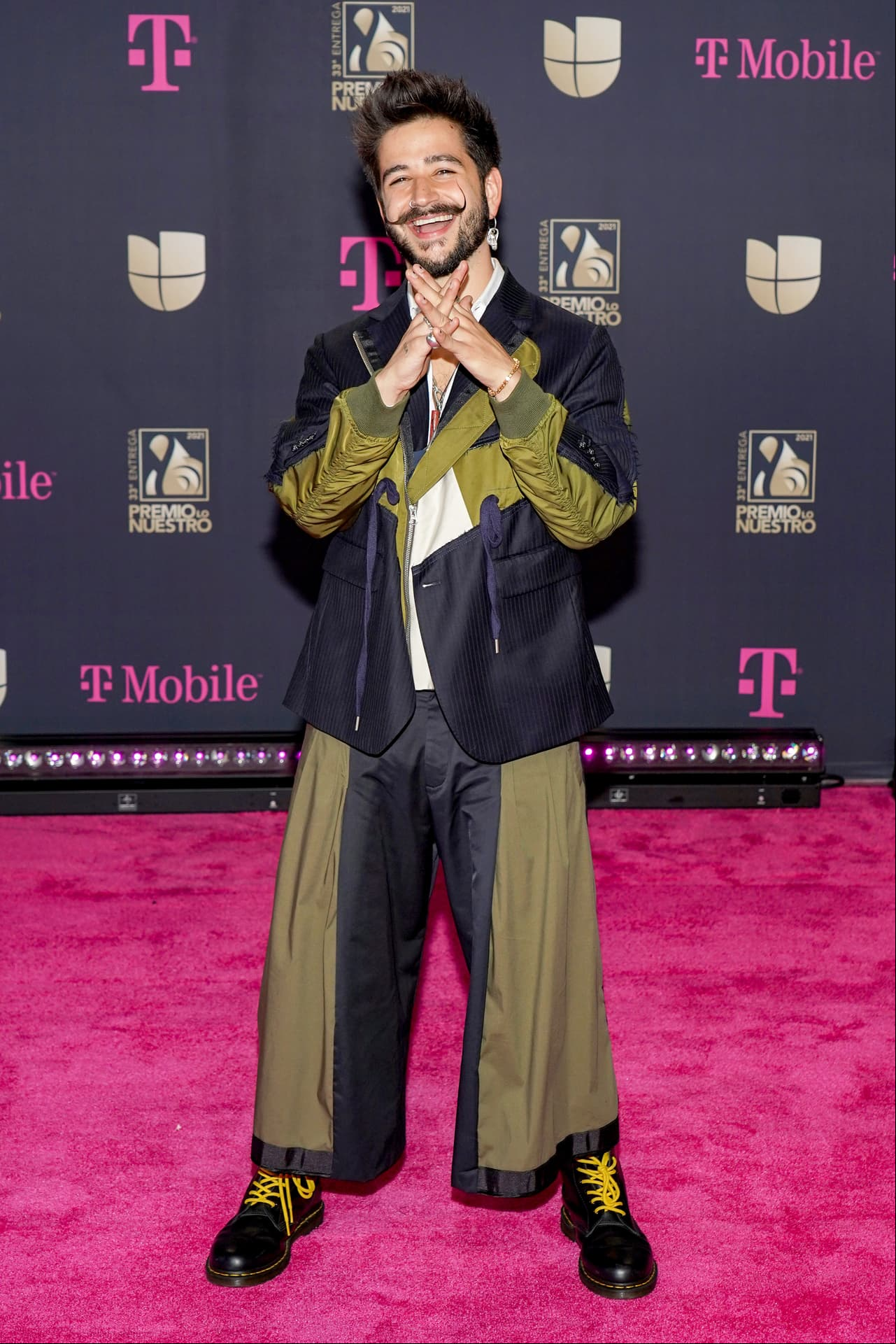 Con su característico estilo urbano, Camilo arribó con la mejor actitud a la alfombra roja de esta entrega. El cantante colombiano lució un traje bicolor; mitad negro y mitad color verde olivo.