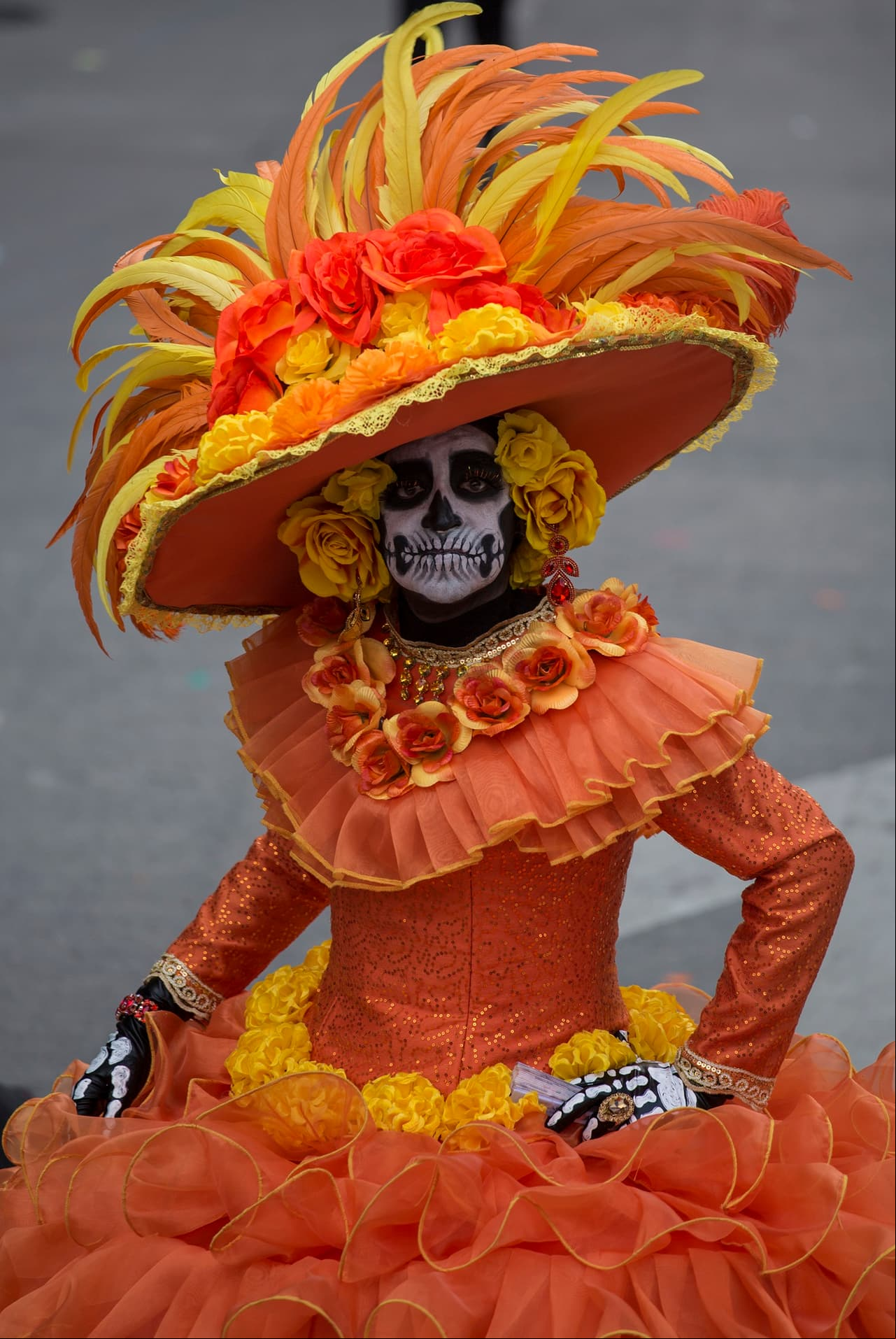José Guadalupe Posada caricaturizó a una calavera sonriente, ataviada con un sombrero de ala ancha adornado con flores y plumas.